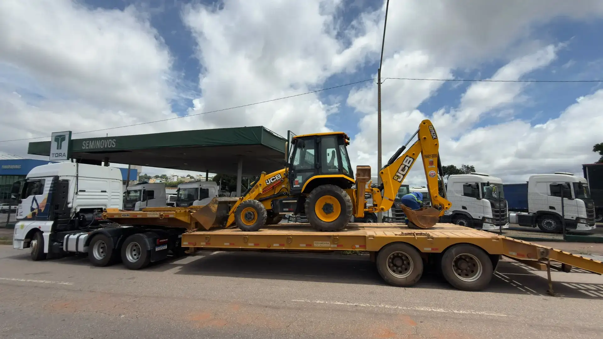 Retroescavadeira JCB embarcada em prancha para transporte até a obra